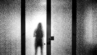 Frau mit Schatten hinter einer Glasscheibe