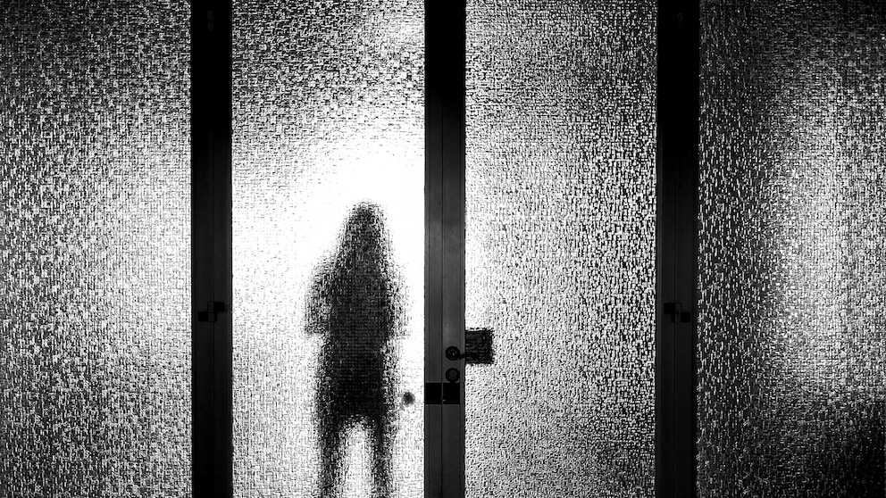 Frau mit Schatten hinter einer Glasscheibe