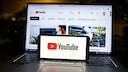 Youtube Logo auf Smartphone und Laptop im Hintergrund