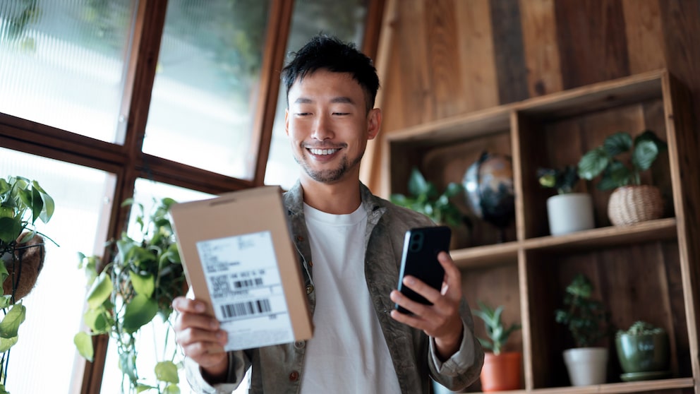 Mann mit Paket und Smartphone in der Hand