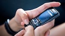 Frau nutzt T9 auf einem Tastenhandy