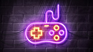 Videospiele 2024 Symbolbild: Controller in Neonlicht vor Bachsteinwand