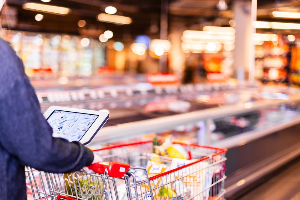 Mann nutzt digitalen Einkaufswagen bei Rewe