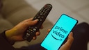 Amazon prime Video Werbung Logo des Dienstes auf Smartphone neben Fernbedienung fü TV
