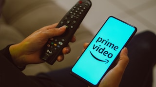 Amazon prime Video Werbung Logo des Dienstes auf Smartphone neben Fernbedienung fü TV