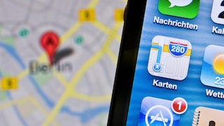 Altes Apple-Maps-Icon auf einem Handy, dahinter ein Kartenausschnitt für Berlin.