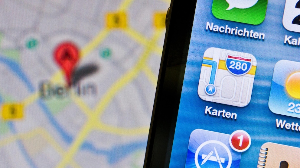 Altes Apple-Maps-Icon auf einem Handy, dahinter ein Kartenausschnitt für Berlin.