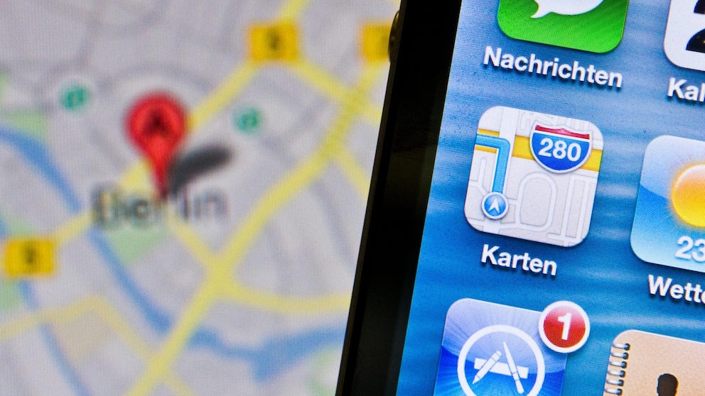 Altes Apple-Maps-Icon auf einem Handy, dahinter ein Kartenausschnitt für Berlin.