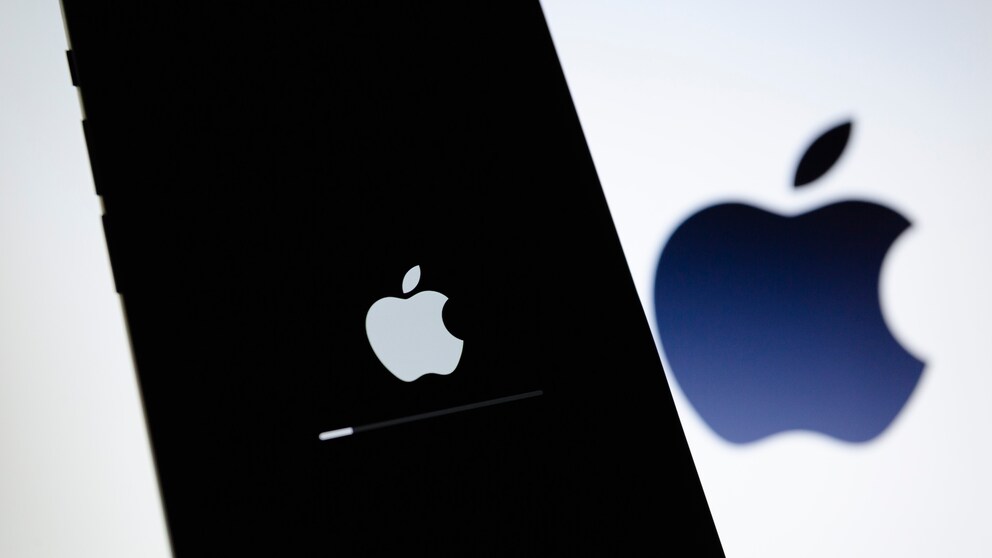 IPhone mit einem Ladebildschirm, im Hintergrund das Apple-Logo.