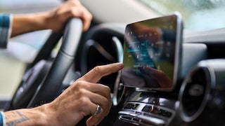 Mann im Auto bedient ein Touchscreen.