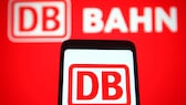 DB Streckennavigator: Logo der Deutschen Bahn im Hintergrund und auf Smartphone
