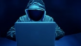 Unheimlich Person mit Kapuze sitzt vor dem Laptop.