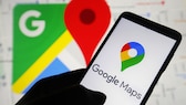 Person hält Handy mit Google-Maps-Logo auf dem Display, im Hintergrund ist die App offen.