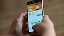 Symbolbild: Zwei Hände halten ein Smartphone, dass die ING-App im App Store zeigt