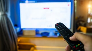 Person richtet Fernbedienung auf einen Fernseher.