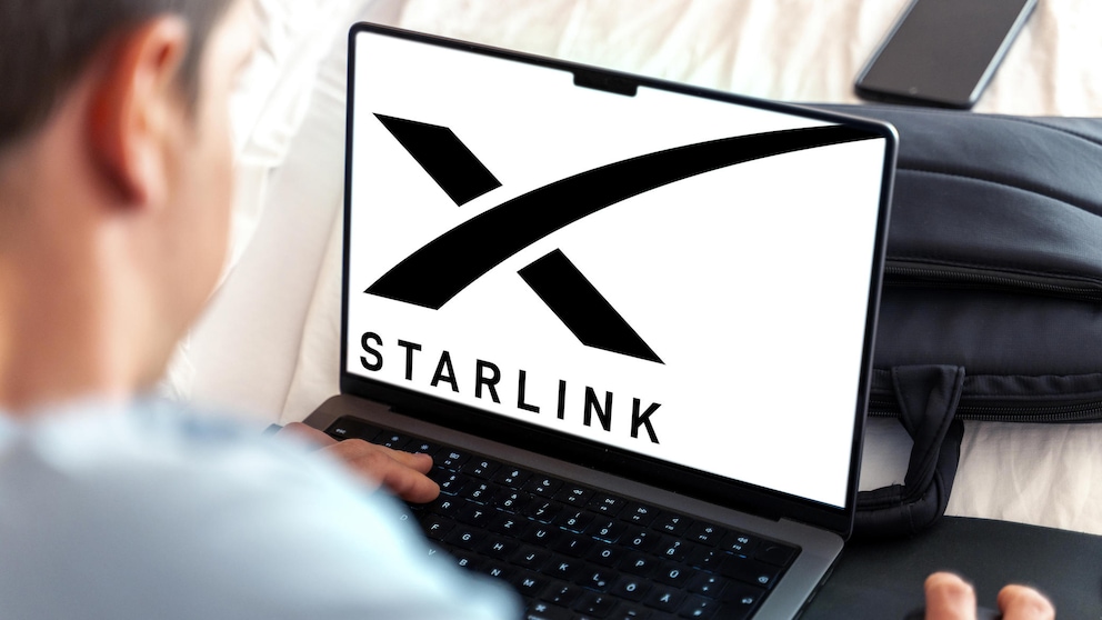 Mann sitzt vor einem Laptop, auf dem das Starlink-Logo zu sehen ist.