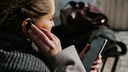 Frau mit Handy in der Hand und In Ear Kopfhörer im Ohr