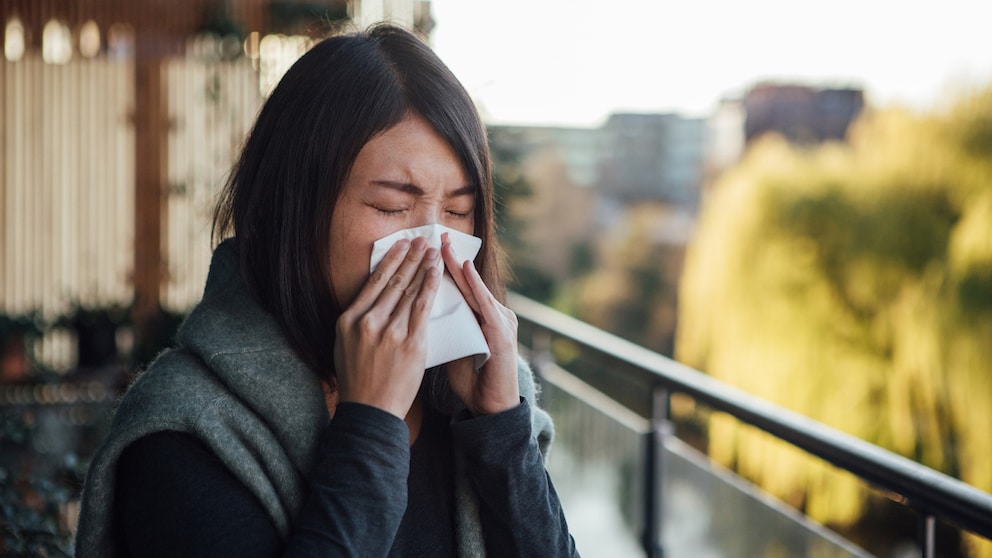 Symbolbild: Eine Frau schnaubt sich wegen einer Gräser-Allergie die Nase