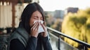 Symbolbild: Eine Frau schnaubt sich wegen einer Gräser-Allergie die Nase