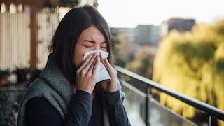 Symbolbild: Eine Frau schnaubt sich wegen einer Gräser-Allergie die Nase
