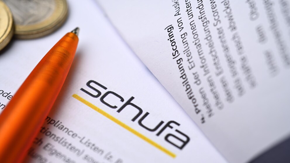 Schufa-Unterlagen neben Stift und Geldmünzen.