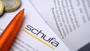 Schufa-Unterlagen neben Stift und Geldmünzen.