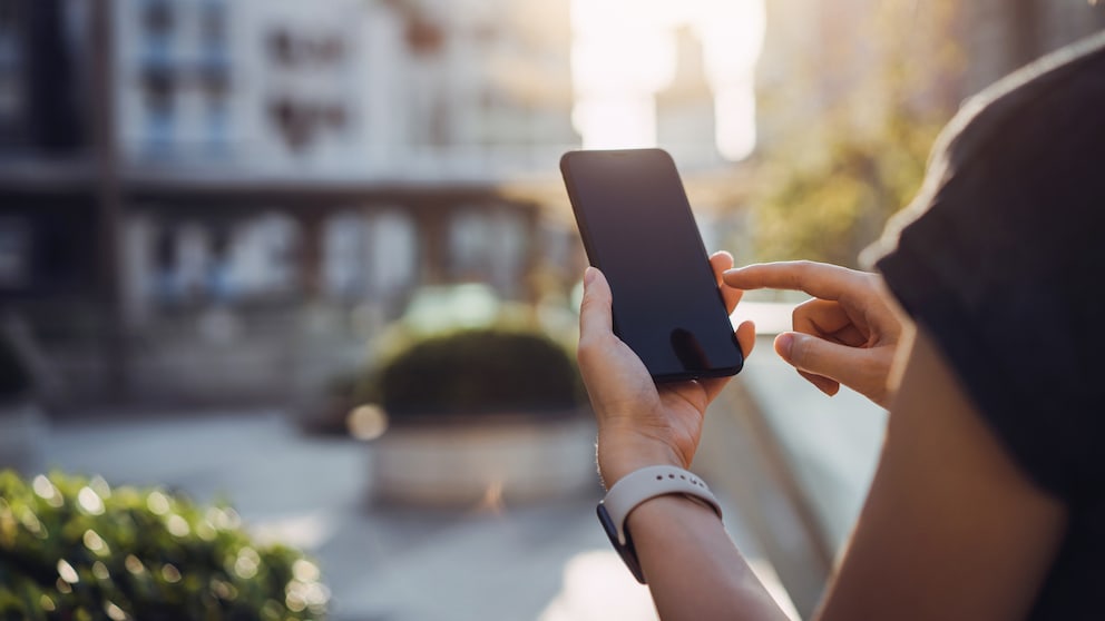 Person nutzt Smartphone im Freien.