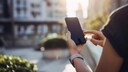 Person nutzt Smartphone im Freien.
