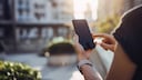 Person nutzt Smartphone im Freien.