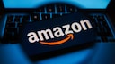 Amazon-Logo auf einem Handy-Bildschirm unter einer Lupe.
