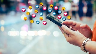 Emojis schweben über dem Smartphone, das eine Person nutzt.