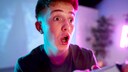 Junger Mann macht überraschten Gesichtsausdruck beim PlayStation-spielen.