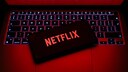 Netflix-Logo auf einem Smartphone, das auf einem Laptop liegt.