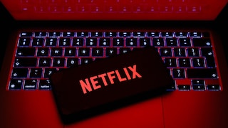 Netflix-Logo auf einem Smartphone, das auf einem Laptop liegt.