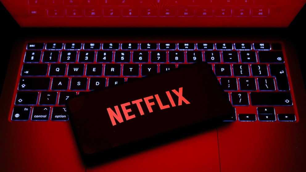 Netflix-Logo auf einem Smartphone, das auf einem Laptop liegt.