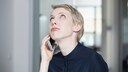 Frau hält ein Smartphone ans Ohr und schaut in die Luft.