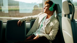 Symbolbild: Mann im Zug hört über Kopfhörer Musik.