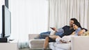 Paar sitzt auf dem Sofa und schaut TV
