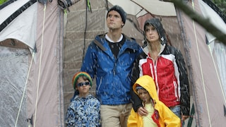 Familie steht bei Regen in einem Zelt und ist unglücklich.