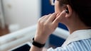 Frau hat Bluetooth-Kopfhörer im Ohr