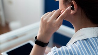 Frau hat Bluetooth-Kopfhörer im Ohr