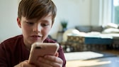 Kind surft auf dem Smartphone im Internet