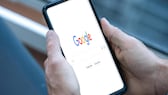 Person hält ein Smartphone mit geöffneter Google-Suche in Händen.