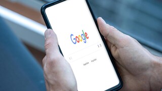 Person hält ein Smartphone mit geöffneter Google-Suche in Händen.