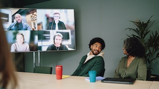 Symbolbild: Meeting in einem Konferenzraum mit Teilnehmenden offline und online