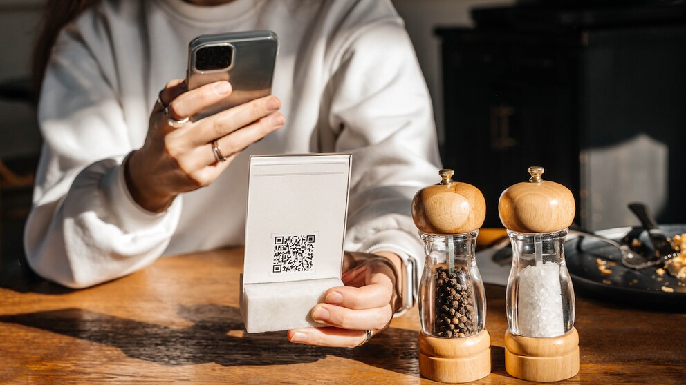 Symbolbild: Frau scannt QR-Code in Restaurant.