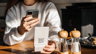 Symbolbild: Frau scannt QR-Code in Restaurant.