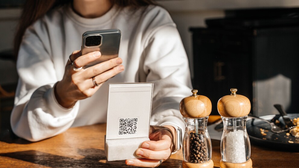 Symbolbild: Frau scannt QR-Code in Restaurant.