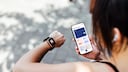 Frau hat eine Smartwatch und ein Smartphone in der Hand