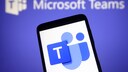 Logo von Microsoft Teams auf einem Handy, im Hintergrund der Schriftzug zum Programm.